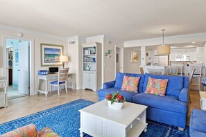 A living room with a blue sofa, a white coffee table, and a blue patterned rug.