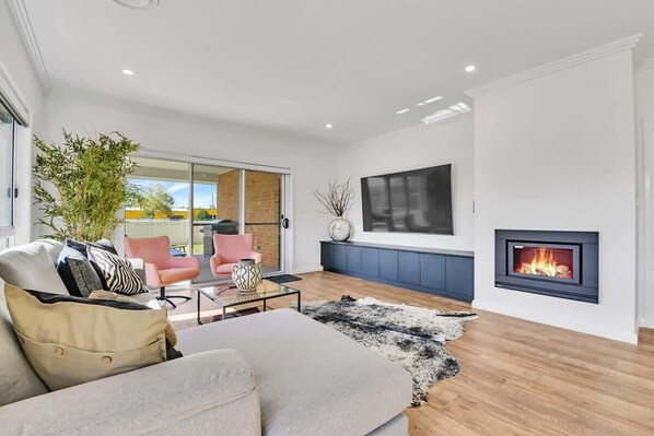 Relax in a spacious living room with a large flat-screen TV, fireplace, and comfortable seating area.