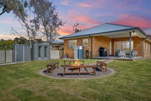 Enjoy a cozy evening by the fire pit in the backyard, surrounded by comfortable picnic tables.