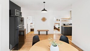 Et moderne køkken med et sort køleskab, en mikroovn og et spiseområde med et træbord og stole.