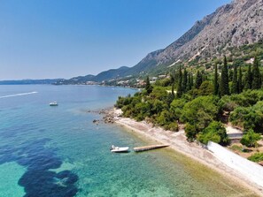 A coastal area with clear waters, boats, and a mountainous backdrop. - Nissaki Olive Press Villas-Family House (Nisaki)