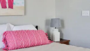 Et soveværelse med en seng, et natbord, en lampe og et billede af sandaler.