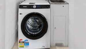 Un lavadero pequeño y funcional con lavadora y secadora Samsung, un lavamanos y un calentador de pared.
