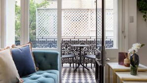 A room with a blue sofa, a checkered floor, a balcony with a lattice fence, and a table with a vase and candles. - Intimate Studio Apartment with Balcony in Glebe (Glebe)