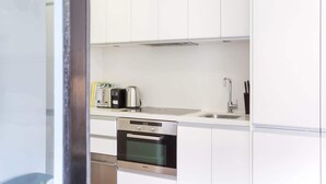 A modern kitchen with white cabinets, a built-in oven, a toaster, and a sink. - Intimate Studio Apartment with Balcony in Glebe (Glebe)