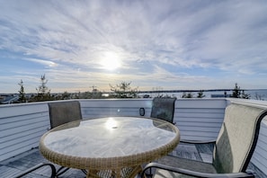 Relax on the patio surrounded by lush trees and a serene body of water.
