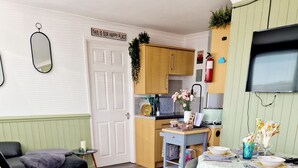 A cozy living room with a sofa, a dining table, and a kitchen area with wooden cabinets and a TV.