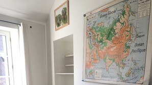 A dining area with a wooden table, wicker chairs, and a large map on the wall. - Charming mezzanine studio (La Chapelle-Saint-Mesmin)