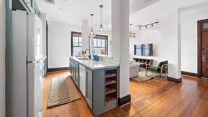 A modern kitchen with a central island, built-in appliances, and pendant lighting. - Stylish Historic Loft, 3 Blocks to The Strand (Galveston)