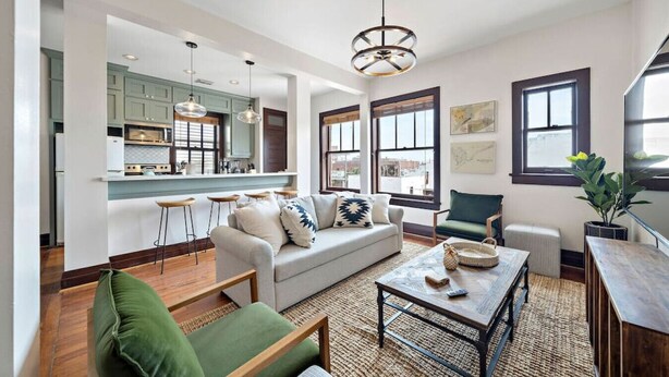 A spacious living area with a sofa, coffee table, and a view of the kitchen. - Stylish Historic Loft, 3 Blocks to The Strand (Galveston)