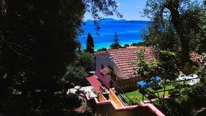 Un quartier résidentiel avec une maison à toit de tuiles rouges, un escalier et une vue sur la mer.