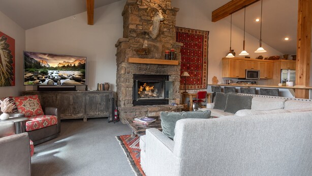 A cozy living room with a stone fireplace, a television, and a sofa. - JHRL - Moose Creek #1, Private Hot Tub (Teton Village)