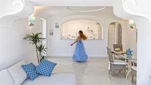 A spacious room with a dining area, a sofa with patterned cushions, and a large potted plant. - Villa dei Lecci Turchese - Luxury private pool villa (Forio)