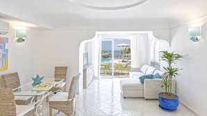 A bright, white interior with a glass dining table, wicker chairs, a sofa, and a potted plant. - Villa dei Lecci Turchese - Luxury private pool villa (Forio)