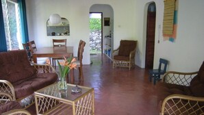 Amplia sala de estar con muebles de mimbre, una mesa de centro de vidrio y vistas al exterior.