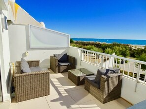 Relax on the balcony with a clear view of the sea, featuring wicker sofas and a small table.