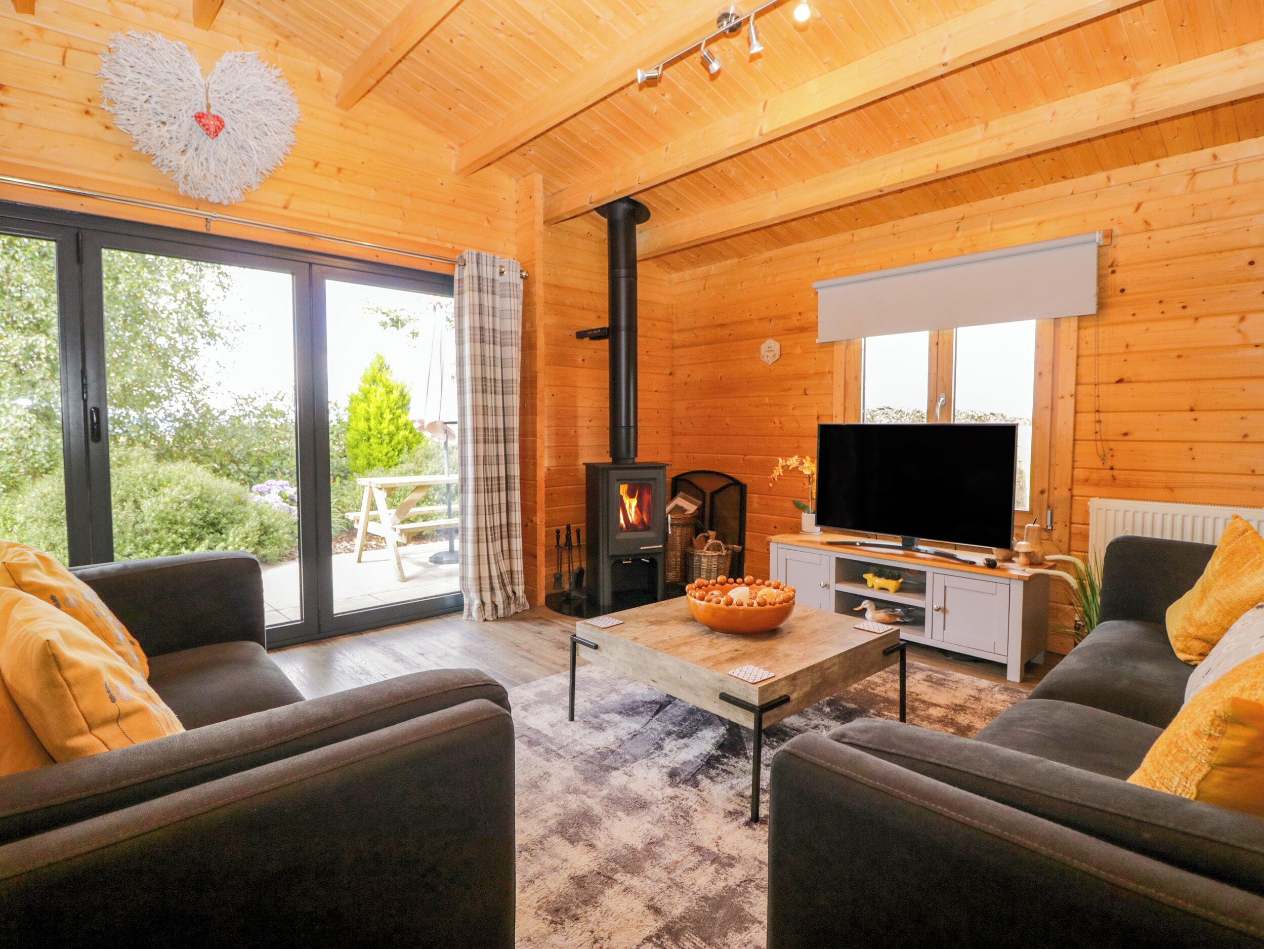 Ein gemütliches Blockhauss-Interieur mit Kamin, Fernseher und Essbereich.