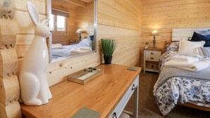 A wooden cabin bedroom with a bed, bedside table, lamp, and a mirror. - Howgills Retreat (Kendal)