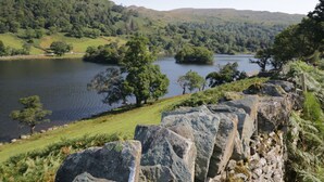 A stone wall with a view of a lake surrounded by hills and trees. - Howgills Retreat (Kendal)