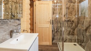 A modern bathroom with a marble shower wall, a wooden door, and a white sink. - Howgills Retreat (Kendal)