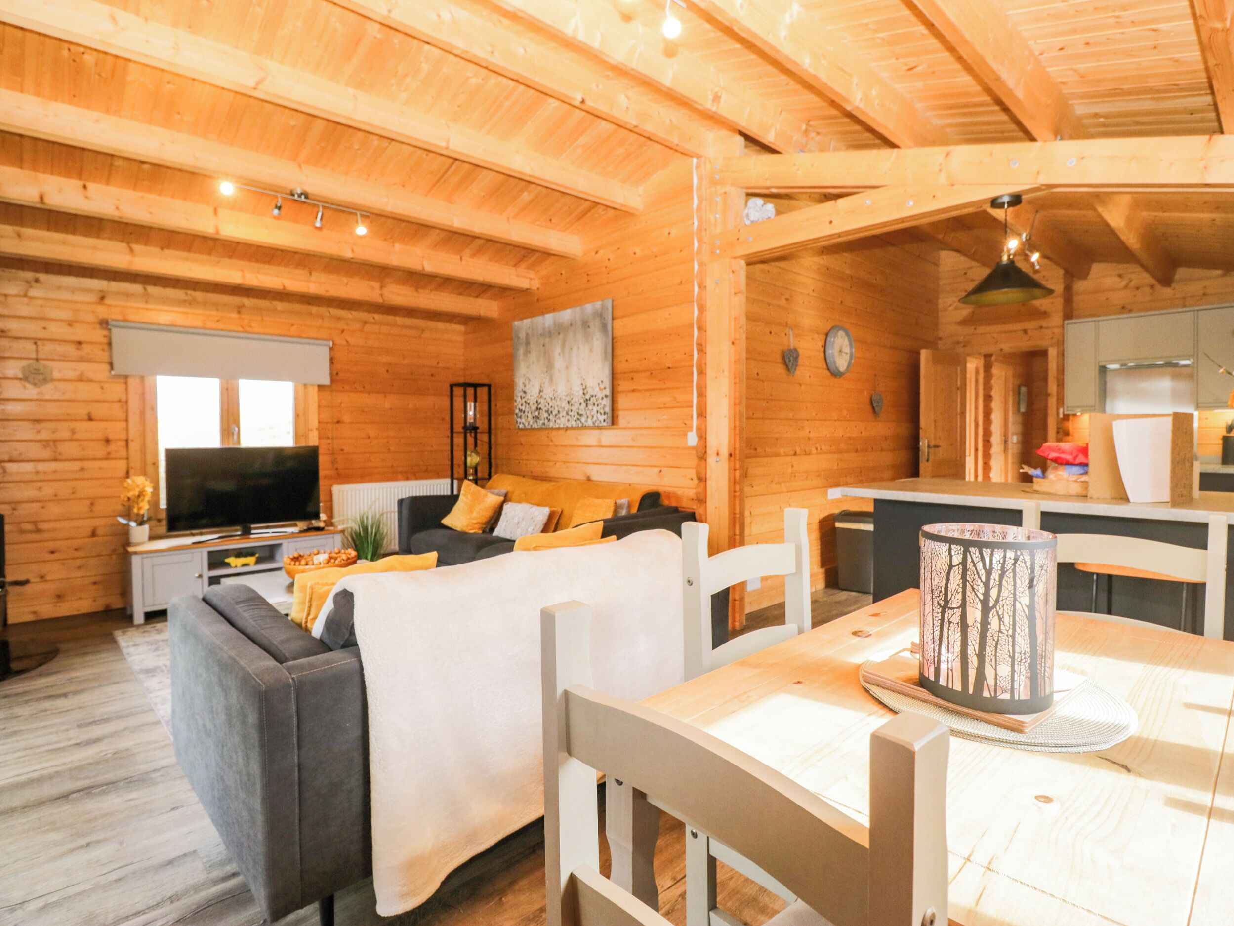 A cozy cabin interior with a living area, sofa, TV, and a dining table.
