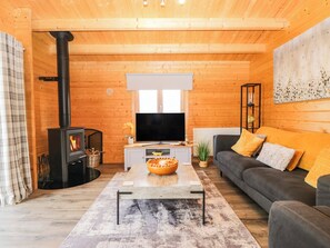 A cozy living room with a fireplace, a flat-screen TV, a sofa, and a coffee table. - Howgills Retreat (Kendal)