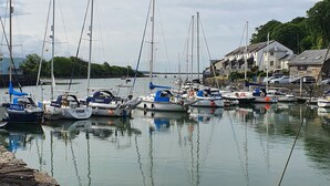 A marina with several sailboats docked, a stone quay, and buildings in the background. - LOVELY 2 BED APARTMENT PORTHMADOG HARBOURSIDE FANTASTIC VIEWS Ffestiniog trains (porthmadog)