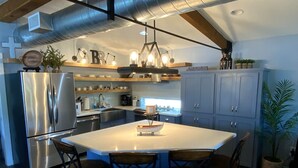 Una cocina moderna con una isla grande, electrodomésticos de acero inoxidable y sillas de madera.