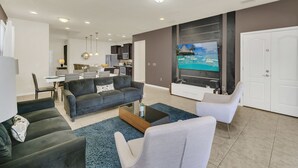 Ein modernes Wohnzimmer mit einer Sofagarnitur, einem Couchtisch und einem an der Wand montierten Fernseher.