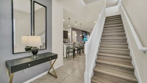 Ein modernes Interieur mit einer Treppe, einem Essbereich und einem Konsolentisch mit einer Lampe.
