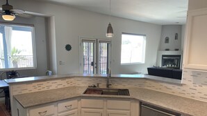 A modern kitchen with white cabinetry, a granite countertop, and a built-in dishwasher.