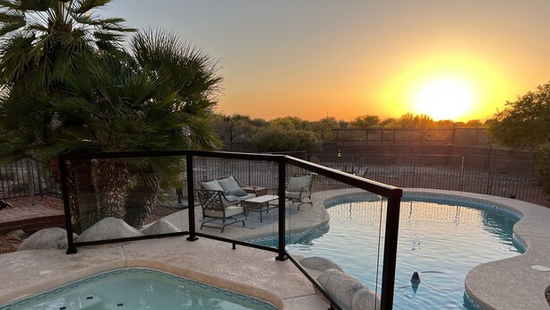 A swimming pool with a hot tub, surrounded by lounge chairs and a palm tree.