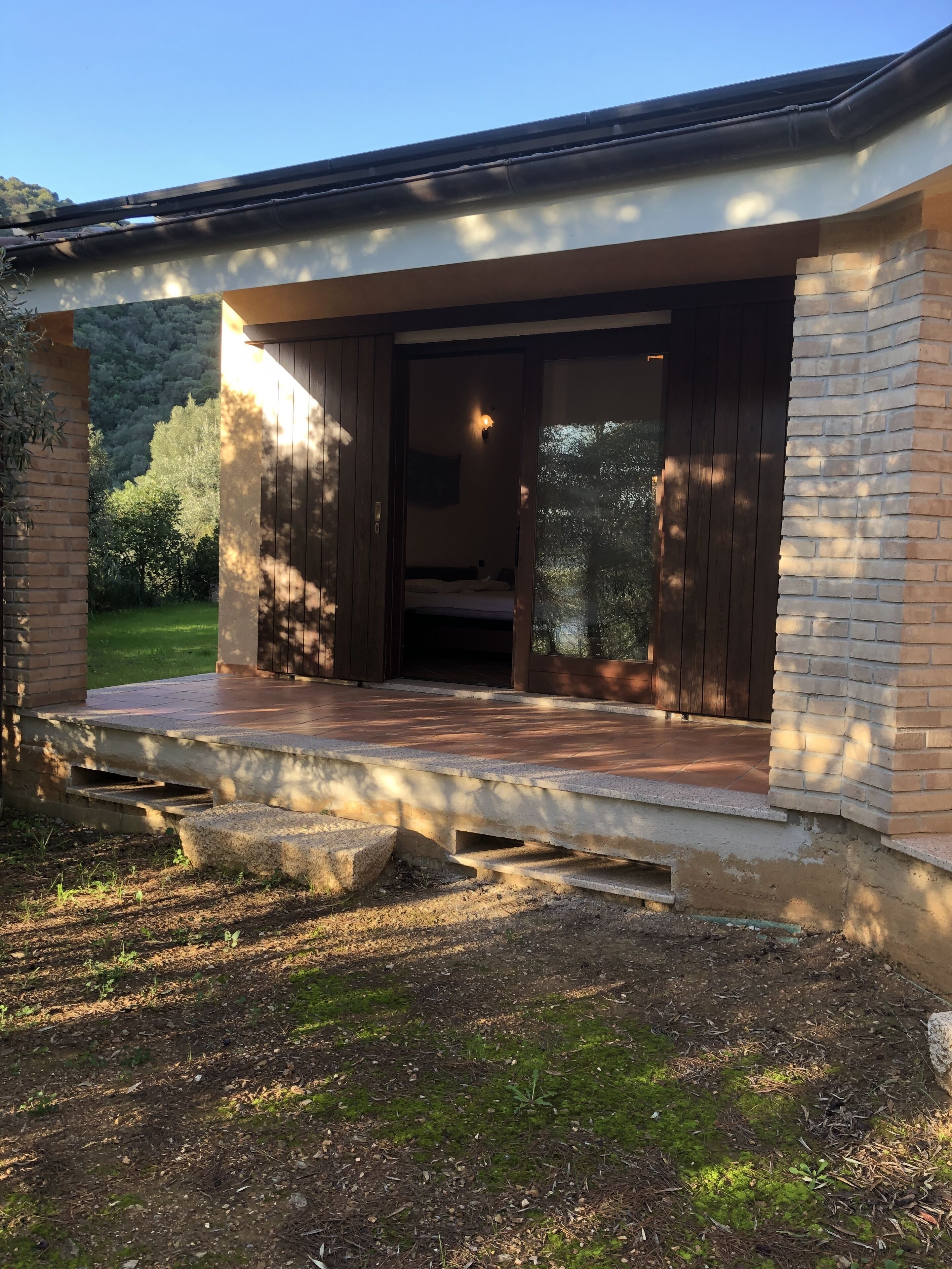 A modern house with a wooden deck, a brick exterior, and a large sliding glass door leading to a bedroom.