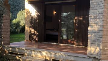 A modern house with a wooden deck, a brick exterior, and a large sliding glass door leading to a bedroom.