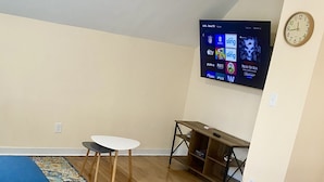 Una sala de estar moderna con un sofá azul, una mesa blanca y un televisor montado en la pared.