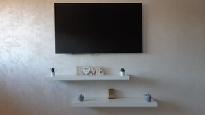 A wall-mounted TV above two white floating shelves with decorative items. - Superb apartment in residence (Marrakech)