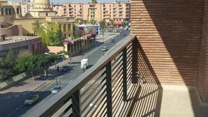 A balcony with a view of a city street, buildings, and a clear sky. - Superb apartment in residence (Marrakech)
