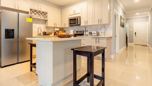Een moderne keuken met witte kasten, roestvrijstalen apparatuur en een centraal eiland.