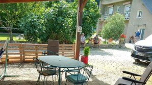 An outdoor seating area with a table and chairs, a small potted plant, and a covered structure.