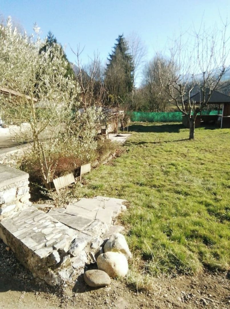 A stone pathway leading through a grassy area with trees and a building in the background.