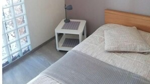 A bedroom with a bed, a nightstand, a lamp, and a window with blinds.