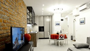 Une cuisine moderne avec un mur en briques, un coin repas avec une nappe rouge et un canapé gris.