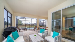 An outdoor patio with white furniture, a small table with a plant, and a glass door leading to a pool area. - (EE2098) SANITIZED 5/4.5 Private Pool & Jaccuzi & Free Waterpark (Kissimmee)