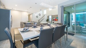 A modern kitchen with a dining area, a staircase, and a large sliding glass door leading to an outdoor patio. - (EE2098) SANITIZED 5/4.5 Private Pool & Jaccuzi & Free Waterpark (Kissimmee)