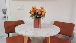 A dining area with a round table, four chairs, and a vase of flowers. - Newly Remodeled Studio in between SF and Napa! (Benicia)