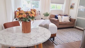 A modern living room with a round marble table, orange leather chairs, a sofa, and a ceiling fan. - Newly Remodeled Studio in between SF and Napa! (Benicia)