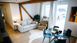 Een moderne woonkamer met een glazen eettafel, een bank, een stoel en een lamp.