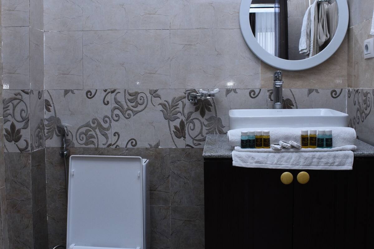 A bathroom with a toilet, sink, and mirror.