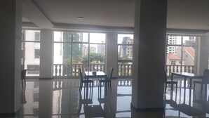 A spacious room with large windows, a polished floor, and a balcony with a railing. - yellow apple hotel (Addis Ababa)