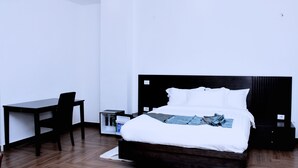 A modern bedroom with a bed, a desk, and a nightstand. - yellow apple hotel (Addis Ababa)